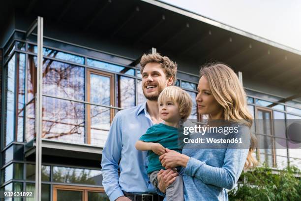 smiling parents with son in front of their home - new home exterior stock pictures, royalty-free photos & images