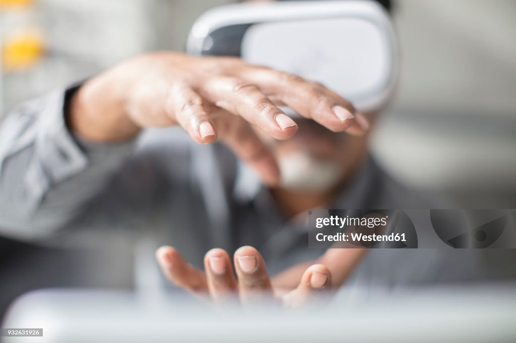 Man shaping with his hands wearing VR glasses in office