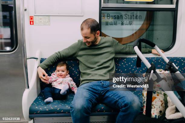 south korea, busan, father and baby girl traveling by subway with a stroller - korean baby girl stock-fotos und bilder
