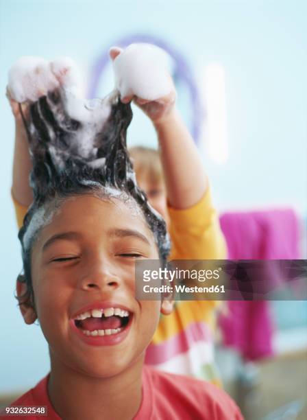 portrait of laughing little boy with foam in his hair - washing hair stock-fotos und bilder