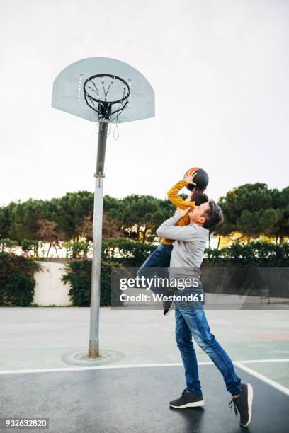 father lifting up son on basketball outdoor court - man with big balls stock pictures, royalty-free photos & images