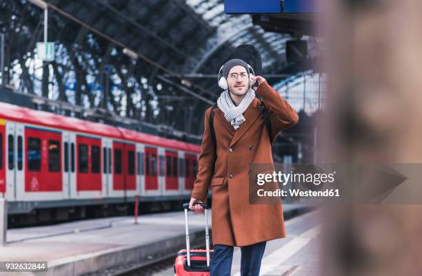 young man with guitar case and headphones at station platform - passenger muzikant stockfoto's en -beelden