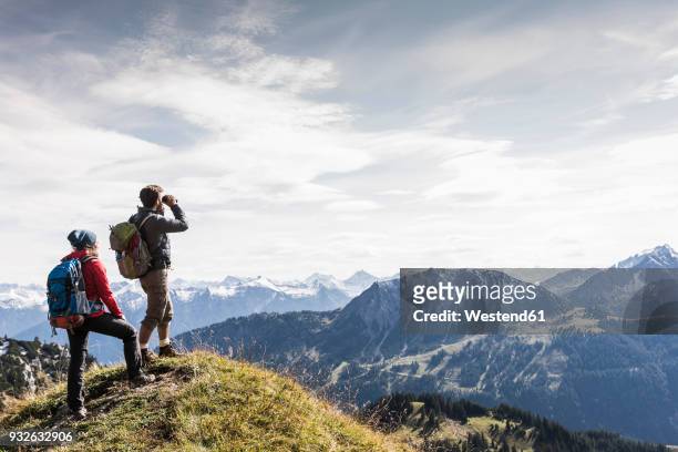 austria, tyrol, young couple standing in mountainscape looking at view - fernglas stock-fotos und bilder