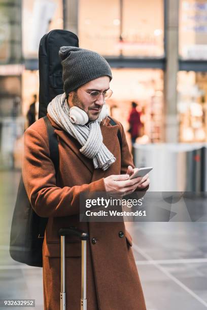 young man with guitar case using cell phone - passenger muzikant stockfoto's en -beelden