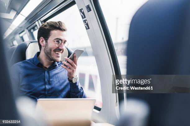 happy businessman in train using cell phone - business man technology travel stockfoto's en -beelden