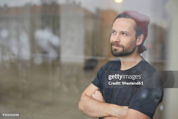 portrait of an artist in his atelier looking out of wondow - contemplation window stock-fotos und bilder