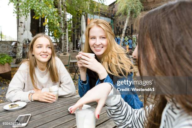 germany, berlin, group of three friends drinking coffee in sidewalk cafe - bar girl stock pictures, royalty-free photos & images