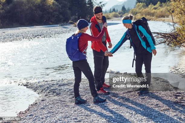 group of friends hiking shaking hands at the riverside - fair play sport foto e immagini stock