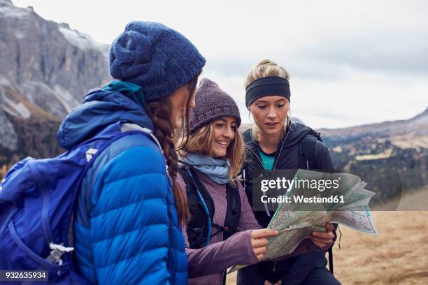 three young women hiking in the mountains looking at map - woman map stock pictures, royalty-free photos & images