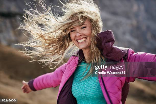 happy young woman leaning against the wind in the mountains - woman jacket stock pictures, royalty-free photos & images