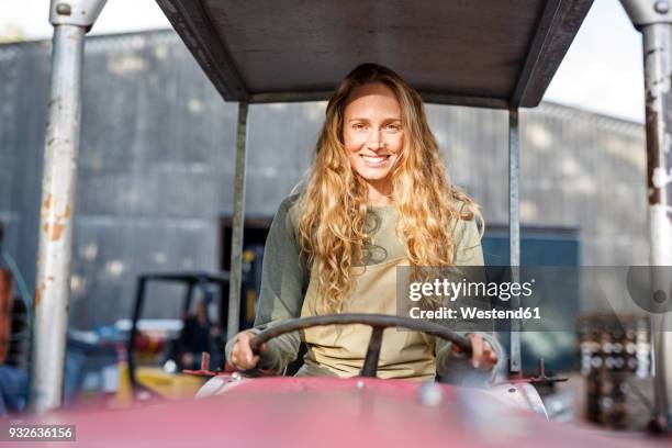 portrait of smiling woman driving a tractor - female driving stock-fotos und bilder