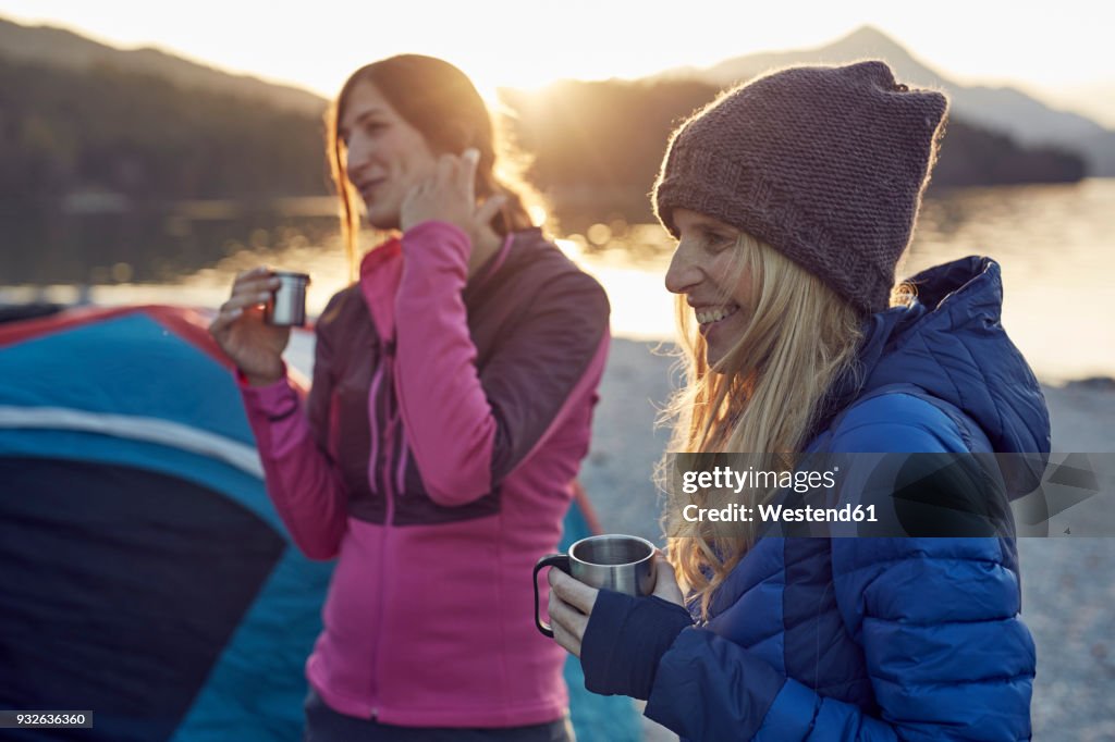 Two female friends at tent holding mugs