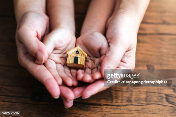 people, family and home concept - close up of woman and girl holding model house - family financial planning stock pictures, royalty-free photos & images
