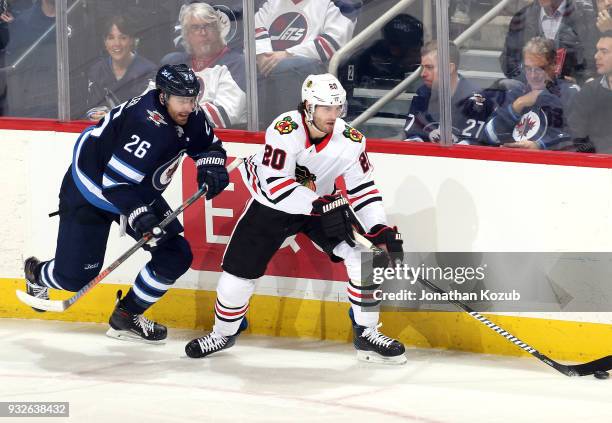 Brandon Saad of the Chicago Blackhawks plays the puck along the boards away from Blake Wheeler of the Winnipeg Jets during third period action at the...