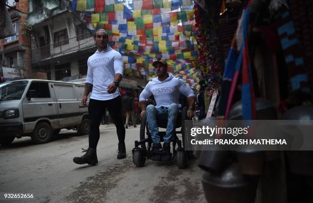 In this picture taken on March 15, 2018 wheelchair-bound Australian Scott Doolan and Matt Laycock make their way along a street in Kathmandu. A...