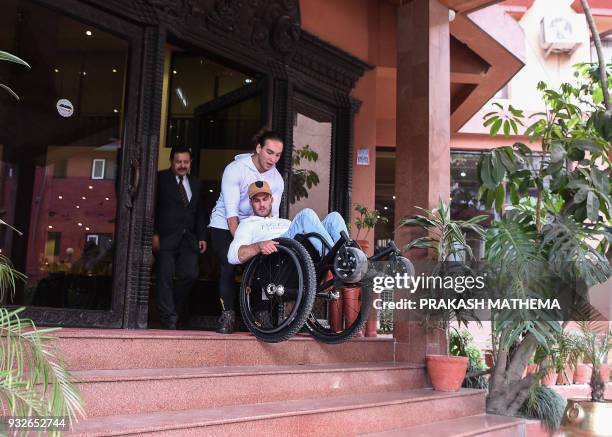 In this picture taken on March 15, 2018 wheelchair-bound Australian Scott Doolan and Matt Laycock make their way down some stairs in Kathmandu. A...