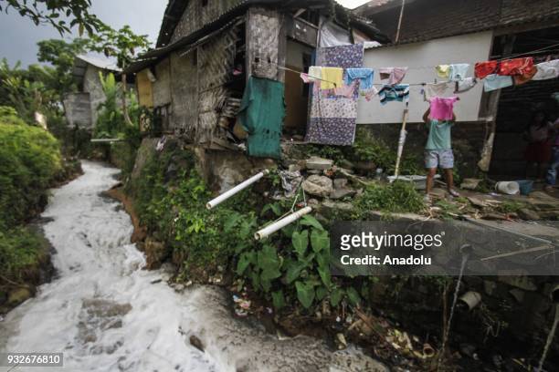 Resident hangs clothes near the flow of tributary covered with textile waste in Sukamaju Village, Majalaya, Bandung, West Java, Indonesia, on March...