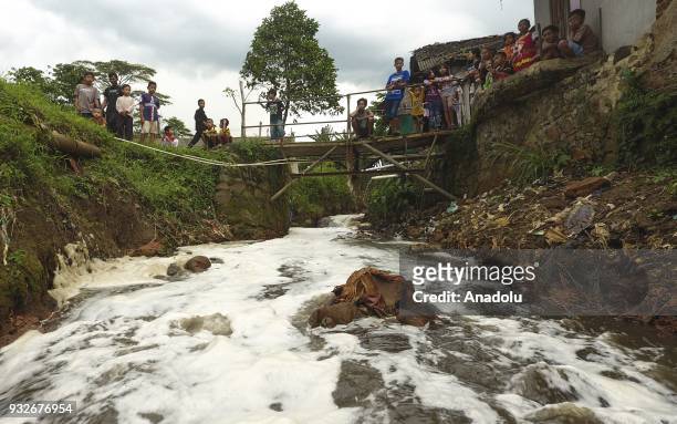 Residents watch the flow of Cikacembang River, which was contaminated by textile factories, on the border of Padamulya Village and Sukamukti Village...