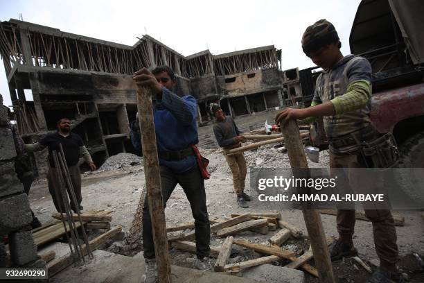 Iraqi workers repair a building on March 15, 2018 eight months after Iraqi forces liberated the city from the control of the Islamic State group...