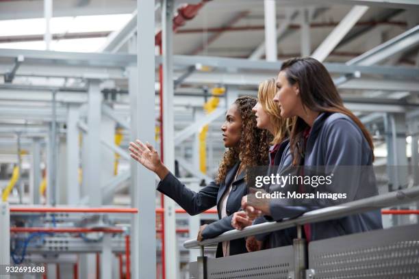 engineers discussing at railing in car plant - leaning stock pictures, royalty-free photos & images