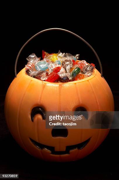 a carved hallowe'en pumpkin filled with candies - bucket stock pictures, royalty-free photos & images