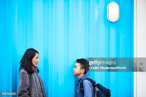 indonesian mother and her 12 years old son talking by the blue wall - 12 13 jaar stockfoto's en -beelden