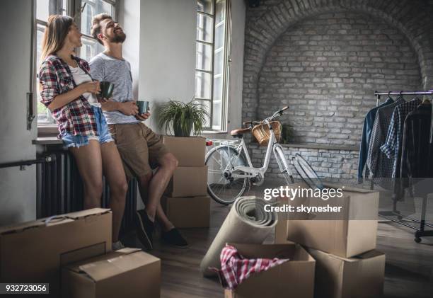 jonge vrolijke paar communiceren na verhuizing naar nieuwe appartement. - man with moving boxes authentic stockfoto's en -beelden