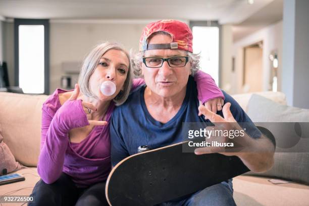 young at heart grandparents: rock and roll sign with skateboard and bubble gum - young at heart stock pictures, royalty-free photos & images