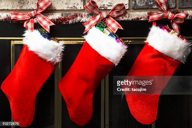 red christmas stockings hung up by tartan ribbon - kousen stockfoto's en -beelden