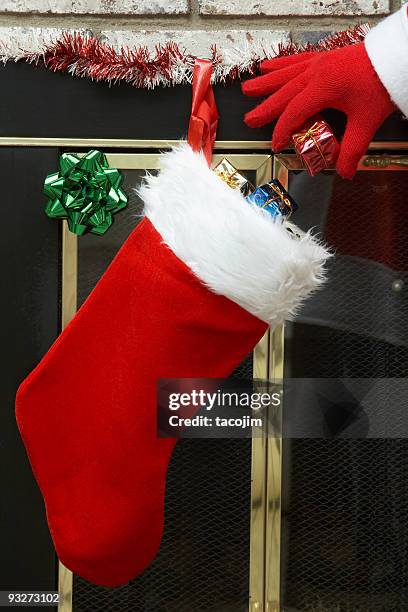 santa putting presents in a christmas stocking - christmas stockings stock pictures, royalty-free photos & images