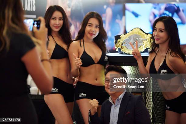 One FC ring girls take selfie with guest at the One Championship exhibition booth at the Sportel Asia Convention on March 13, 2018 in Singapore.