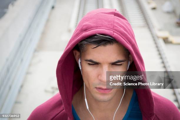 young man wearing ear phones and hooded top - hoodie headphones - fotografias e filmes do acervo