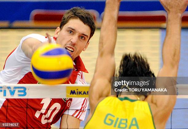 Marcel Gromadowski of Poland spikes the ball past Gilberto Godoy Filho of Brazil during their match at the men's Grand Championship Cup volleyball...
