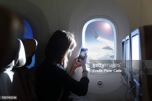 girl taking photo out of airplane window - aeroplano foto e immagini stock