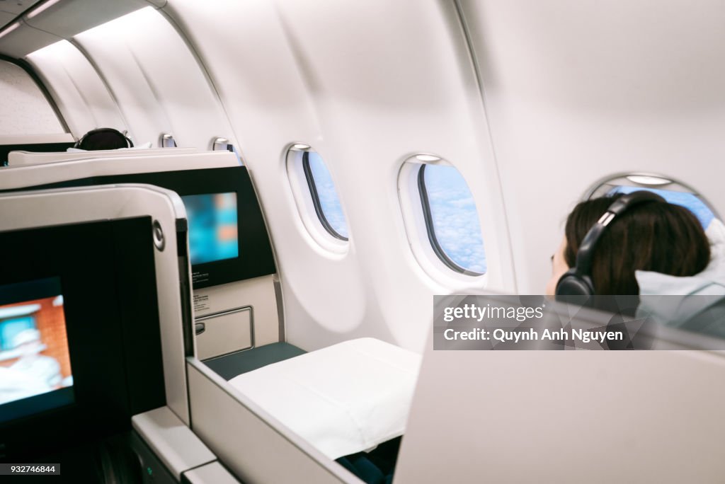 Passenger using on board entertainment on business class of  aircraft