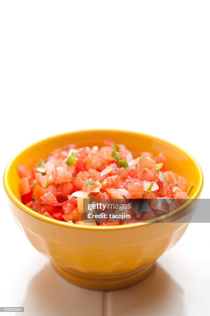 Yellow bowl of salsa on a white background