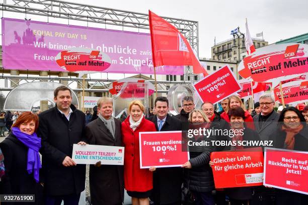 The new German Labour Minister Hubertus Heil and German Family Minister Franziska Giffey hold a placard reading "Women earn 100%!" as they attend a...