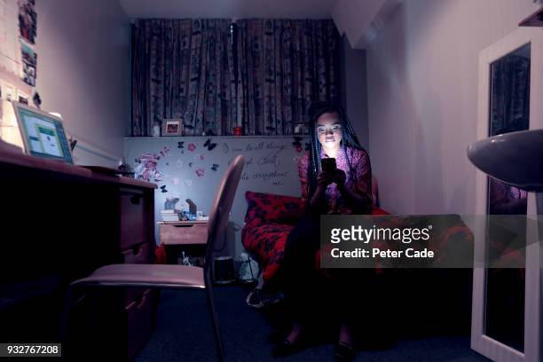 student in room, on phone, at night - online bullying foto e immagini stock