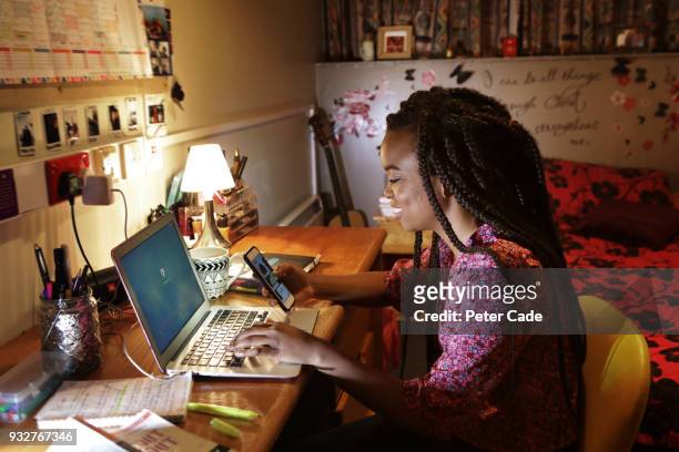 student sat at desk in bedroom looking at phone - beleuchtet zuhause drahtlos stock-fotos und bilder