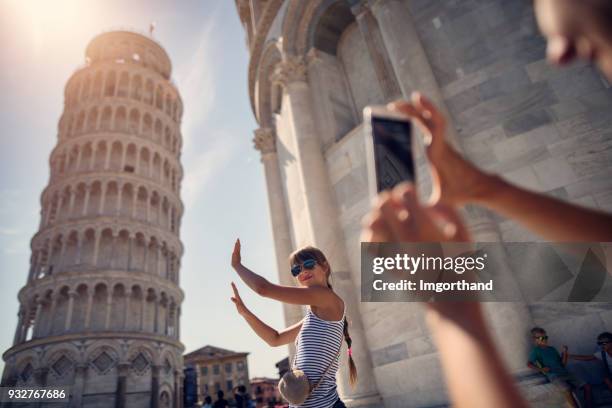 holding up photos of the leaning tower of pisa - mass tourism imagens e fotografias de stock
