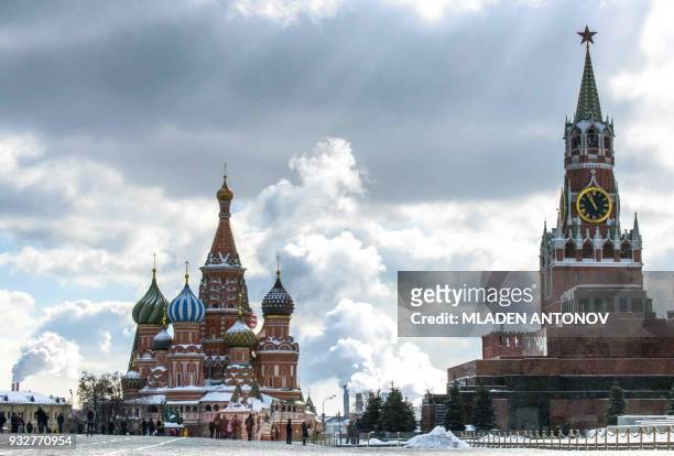 People walk in front of St. Basil's Cathedral and the Kremlin on Red Square in Moscow on March 16, 2018. Russia will vote for President on March 18....