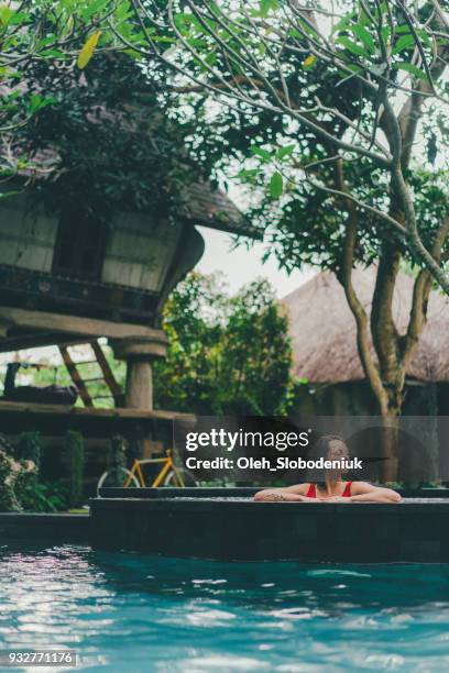 woman in the red swimsuit in swimming pool - bali spa stock pictures, royalty-free photos & images