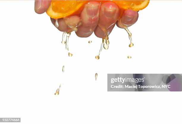 close-up view of a hand squeezing orange. - squeezing imagens e fotografias de stock