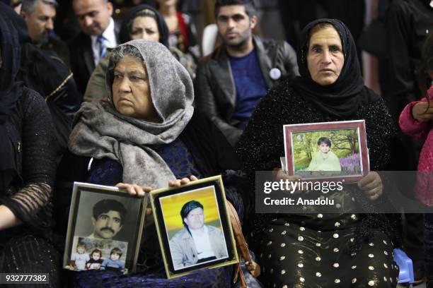 Women hold pictures of their relatives as people visit the Halabja Martyrs Monument to commemorate the victims of Halabja massacre due to 30th...