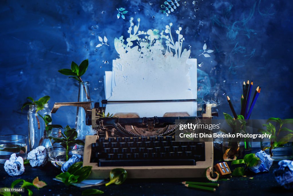 Creative writer workplace with a typewriter and growing plants. Imagination garden concept. Dark still life with action and copy space.