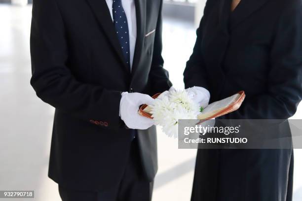 close up of bereaved holding bible and white flower - funeral flowers stockfoto's en -beelden