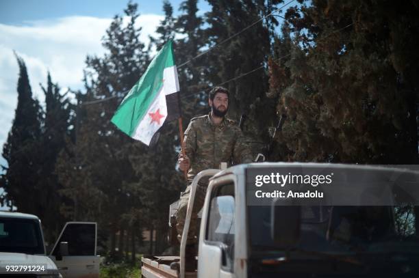 Member of Free Syrian Army , backed by Turkish Armed Forces, is seen on a pick-up truck as other FSA members prepare guns for firing to hit...