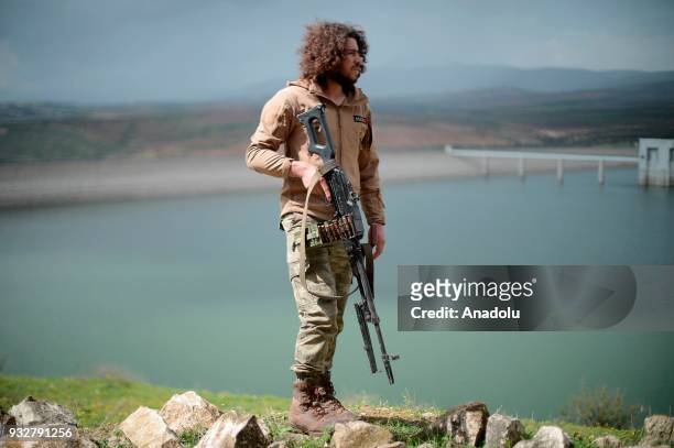 Member of Free Syrian Army , backed by Turkish Armed Forces, patrols as other FSA members prepare guns for firing to hit YPG/PKK-Daesh terrorists...