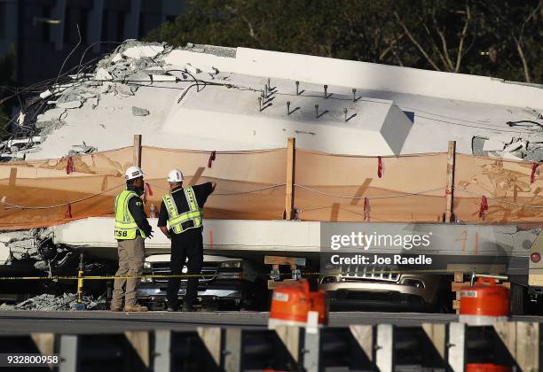 Members of the National Transportation Safety Board investigate the scene where a pedestrian bridge collapsed a few days after it was built over...