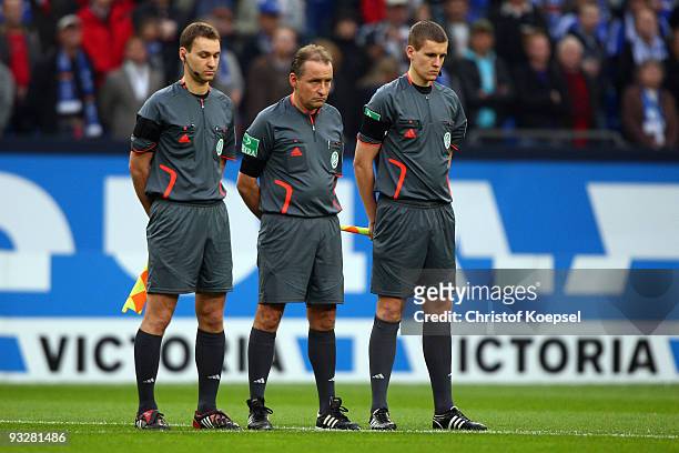Linesman Bastian Danker, referee Lutz Wagner and linesman Daniel Siebert stand up for a minute's silence after the death of Robert Enke during the...